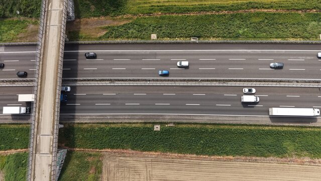 Aerial View of Highway Traffic: Cars and trucks navigate a multi-lane highway with a bridge overhead, showcasing the flow of transportation across the landscape.