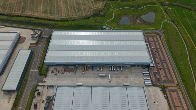 Aerial view of the Appleby Magna industrial park featuring a large warehouse with loading docks, parked trucks, and surrounding green fields Appleby Magna, England, United Kingdom.
