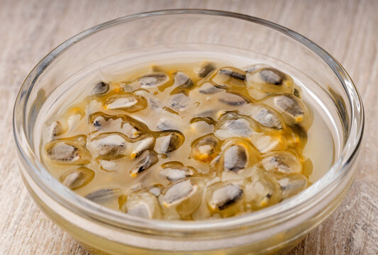 Macro detail of ripe passion fruit pulp (Passiflora ligularis), a healthy exotic food on a light wood background.