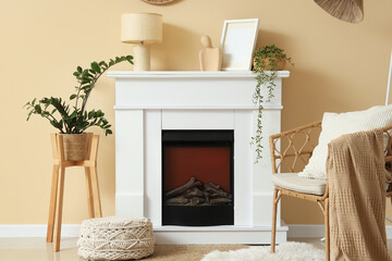 Obraz premium Fireplace, wicker chair and houseplants in interior of living room