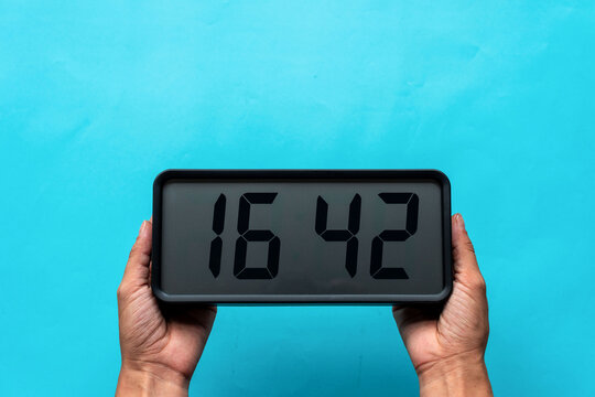 Digital clock held by hands.