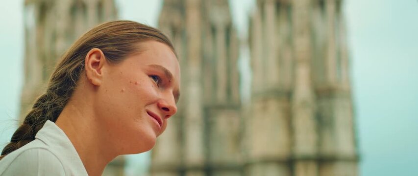 Woman smiling while observing cathedral spires in the background