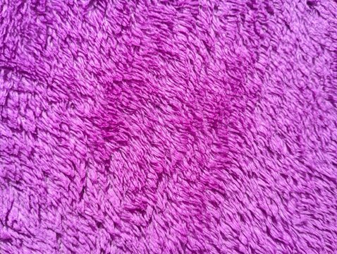 Close up macro shot of a bright purple fuzzy fabric texture.