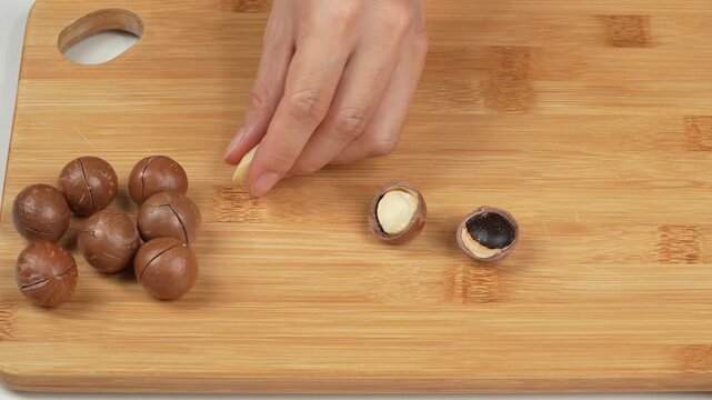 Cracked macadamia nuts with kernels split in half on wooden background.