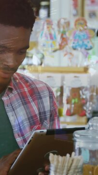 Vertical video: Shop clerk tapping tablet, scrolling, showing digital prices updating sweets stock