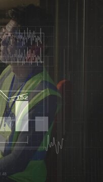 Vertical video: Tech sitting in safety vest red muffs unit showing waves and bars at 188 for safety