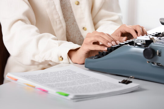 Female screenwriter using vintage typewriter at table in office, closeup
