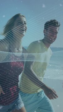 Vertical video: Group walking beach cam panning sparking wave over group and dots for travel