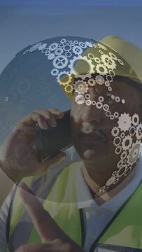 Vertical video: Site tech raising phone coordinating turbine repair gears overlay obscuring helmet