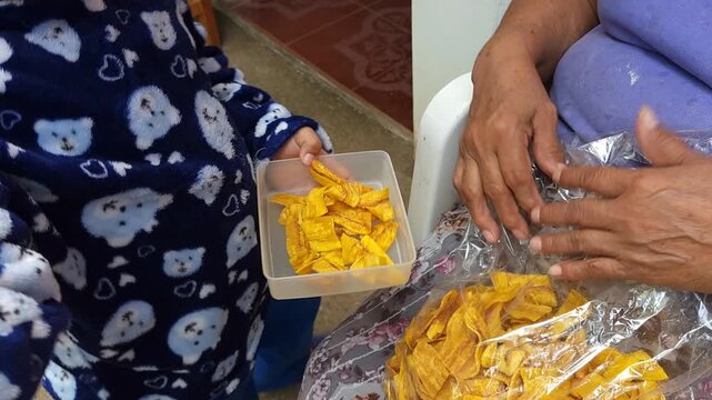 Woman serving freshly fried plantains into a child's container