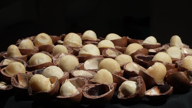 Cracked macadamia nuts group on black background with empty space for text.