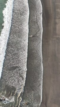 Vertical drone video of beach waves