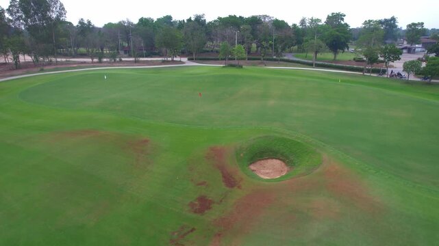 Aerial drone view flying over empty golf course surrounded by lush greenery. 