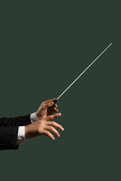 Hands of male conductor with baton on green background