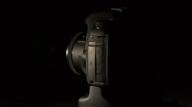 Dark and moody: DSLR camera rotates against black with hard side light