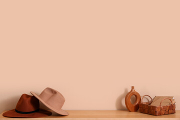 Stylish hats with books and vase on shelf near beige wall © Pixel-Shot