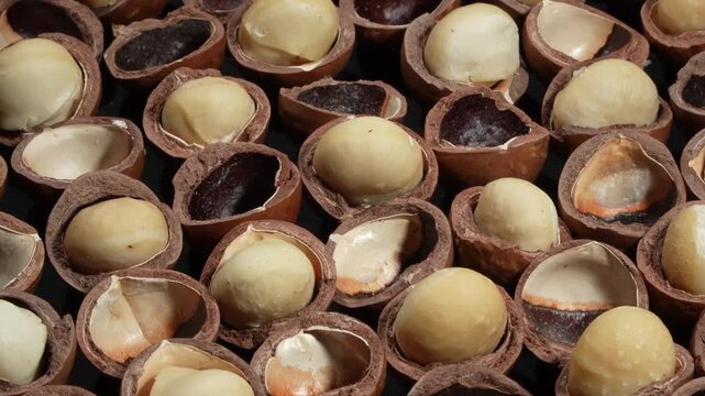 Macro of premium cracked macadamia nuts with kernels background.