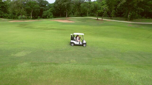 Drone view of golfers people riding together in golf cart on course. 