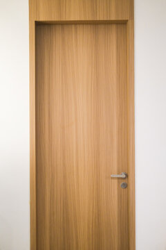 House door with HPL wood grain finish framed by clean white walls, combining modern practicality with natural warmth for a stylish home entryway