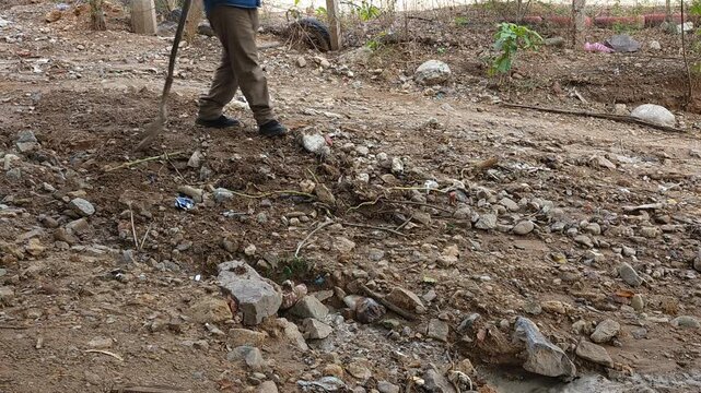 Man cleaning up trash washed into a ravine after rain