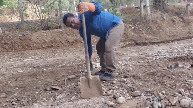Man lifting and throwing large rocks to clear the ground