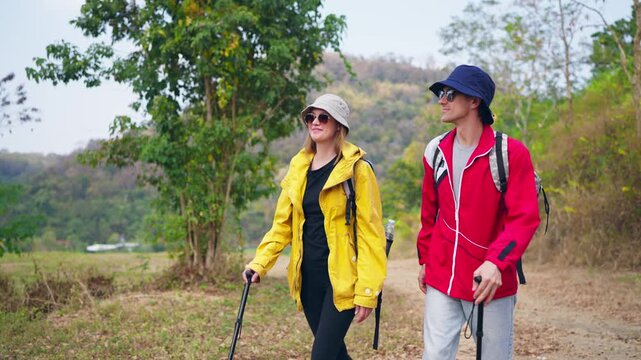 Caucasian hikers with backpacks walking together on a trail in mountains.
