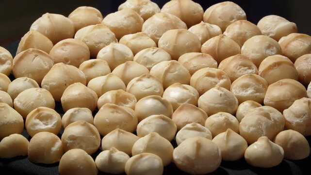 Group of peeled macadamia nuts kernels on black background background.