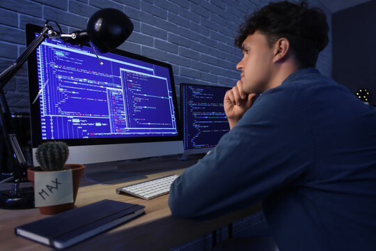 Male programmer working with computer in office at night