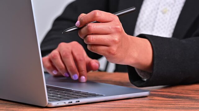Close-up of businesswoman hands using laptop trackpad and holding a stylus pen in the office