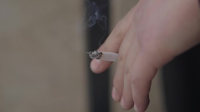 Hand holding cigarette outside in a city location