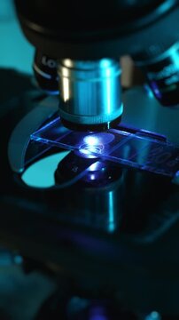 Close up of microscope analyzing sample slide as lab technician changes specimen, laboratory research process in medical and scientific environment.