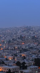 Fototapeta premium Middle Eastern city skyline view at twilight with building lights and copy space sky for urban planning documentary and travel guide background