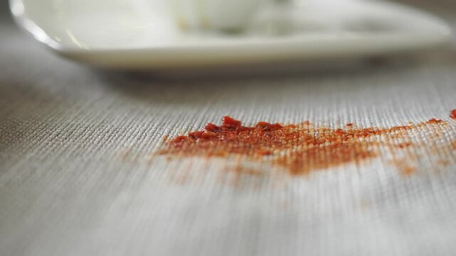 Red spice mess on tablecloth at cafe during lunch hour