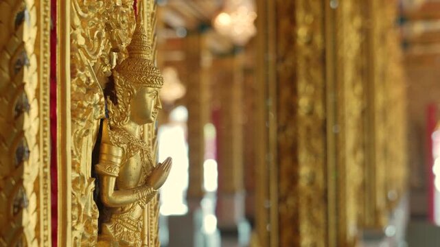 Mythical protector figures across temple wall gilded high relief gold surfaces mirrored details carved borders Thai sacred design reverence grandeur.