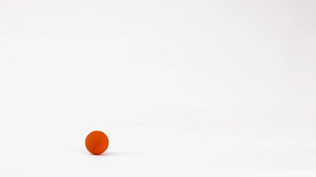 Vibrant Orange Ball Bouncing and Rolling Across a White Background