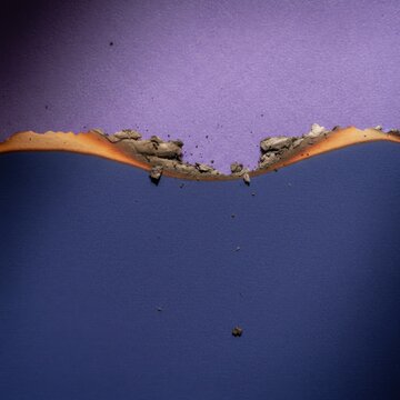 Burnt indigo paper edge with charred orange singe marks on purple background for creative art design and historical documentary graphic element with copy space