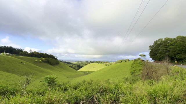 Lush green hills and pastures in the Atherton Tablelands near Upper Barron, tropical North Queensland, Australia. Scenic rural landscape with farmland and rolling countryside.