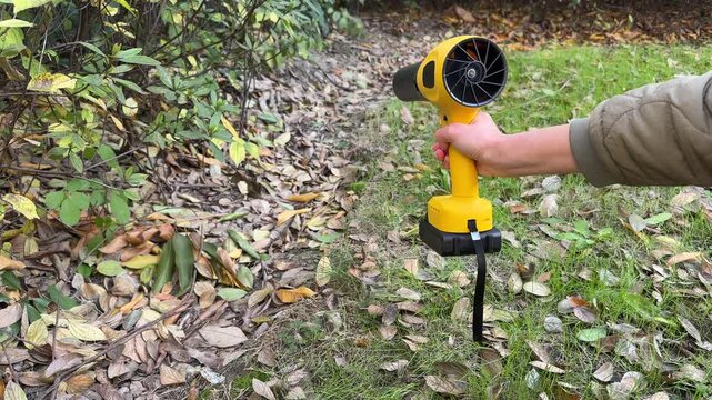 Close-up shot of a gardener's hand holding a compact wireless cordless electric blower