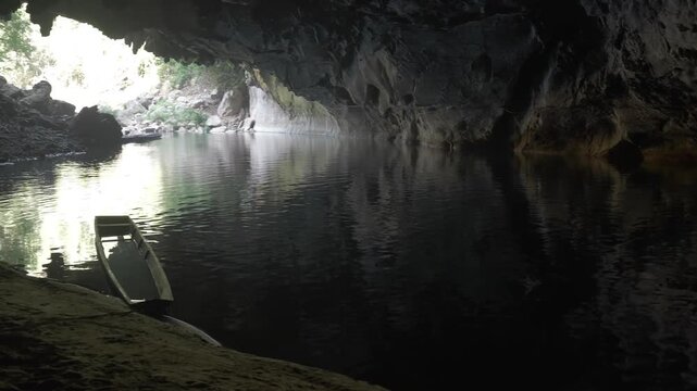 Panning from the entrance of Kong Lor cave to the tour boats on the bank in the darkness with sunlight filtering through.
