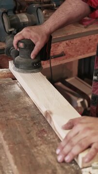 Vertical video. Sanding wood. Joiner tool. Man hand planing board surface with professional industry lumber equipment in workshop.