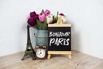 Bonjour Paris text written on easel with eiffel and alarm clock on wooden background © may1985