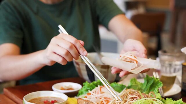 Asian Woman Preparing Fresh Vietnamese Spring Rolls with Chopsticks in Restaurant