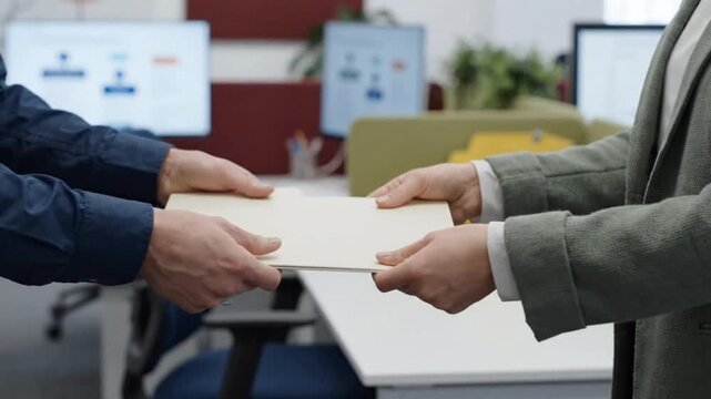 Close-Up of Hands Exchanging Blank Folder in Modern Office Aisle