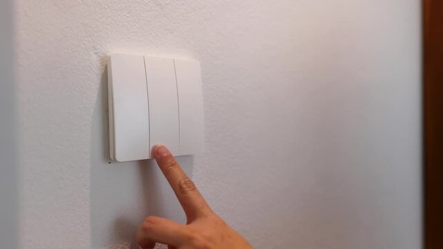 Close Up of a Finger Pressing a White Light Switch Button