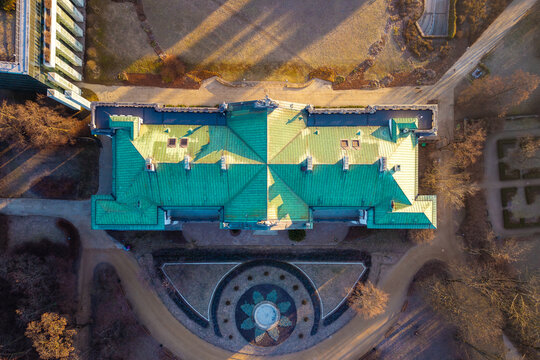 Aerial view of the geometric green copper roof of Krasinski Palace and surrounding park grounds with long shadows in Warsaw, Masovian Voivodeship, Poland.