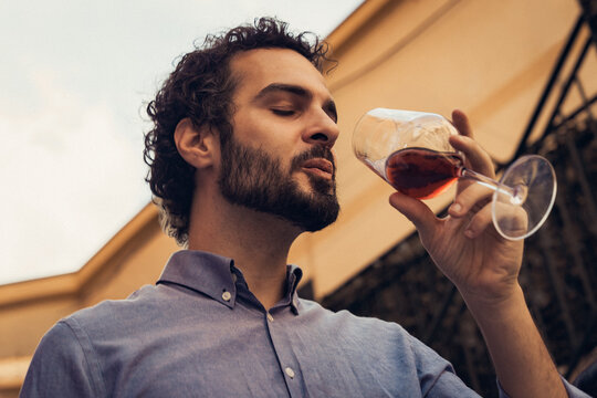 Young man smelling red wine in glass during outdoor wine tasting