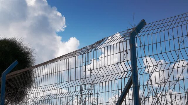 The Israeli West Bank separation barrier under a bright sky with clouds.This security fence marks the boundary between Israel and the Palestinian Authority