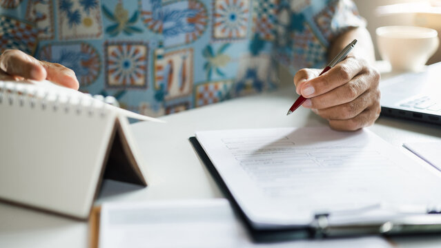 close up shot, casual man working at home learning information about online business, reading documents, making plan to start own business online, E-commerce