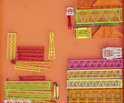 Aerial view of colorful crane lattice boom sections arranged on a bright orange industrial surface in Taiwan.