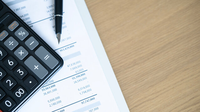 Calculator and pen pointing at financial statement on wooden desk, business accounting, audit and expense analysis concept with blank copy space.
